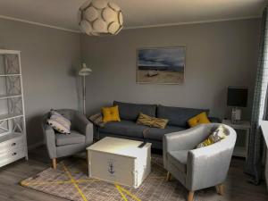 ein Wohnzimmer mit einem Sofa und 2 Stühlen in der Unterkunft 168 Salzwiese Ferienwohnung in Accumersiel