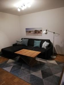 ein Wohnzimmer mit einem schwarzen Sofa und einem Couchtisch aus Holz in der Unterkunft Appartements am Park in Bad Krozingen