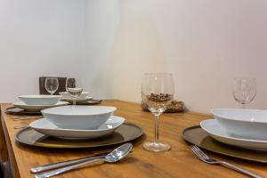 una mesa de madera con platos, tazones y copas de vino en Goldcentral Apartment Dob en Budapest