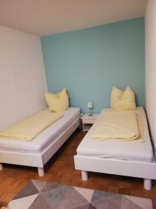 2 Betten in einem Zimmer mit blauer Wand in der Unterkunft Appartements am Park in Bad Krozingen
