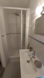 La salle de bains blanche est pourvue d'un lavabo et d'une douche. dans l'établissement L'appartement de l'église, à Saintes-Maries-de-la-Mer
