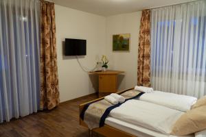 sypialnia z 2 łóżkami, telewizorem i zasłonami w obiekcie Hotel Eleon w mieście Bad Teinach-Zavelstein
