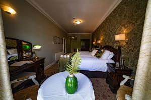a hotel room with two beds and a table with a vase on it at Fernhill House Hotel & Gardens in Clonakilty