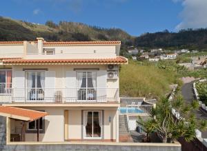 a white house with a balcony and a swimming pool at Arco da Calheta Villa in Arco da Calheta