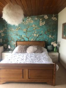 uma cama num quarto com uma parede floral em Ballygally Seaview Cottage em Larne
