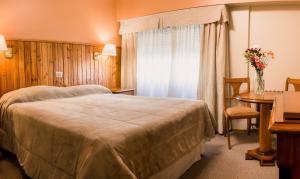 a bedroom with a bed and a table with a vase of flowers at Hotel Nevada in San Carlos de Bariloche