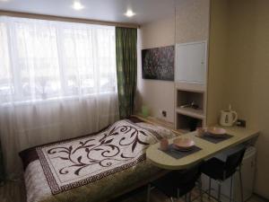 um quarto com uma cama, uma mesa e uma janela em Апартаменты СВ "Атлант" 2 em Tver