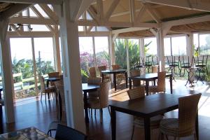 a restaurant with tables and chairs and windows at Les Bungalows les Vanilliers, Sud Sauvage avec piscine in Saint-Joseph