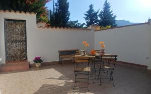 een patio met een tafel en stoelen en een witte muur bij Ciuri ri zagara in Cinisi