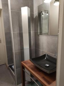 La salle de bains est pourvue d'un lavabo noir et d'un miroir. dans l'établissement Le Balcon du Parc, entre Lourdes et Gavarnie, à Argelès-Gazost