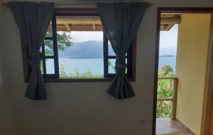 a window in a room with a view of the water at Beautiful day suítes in Ilhabela