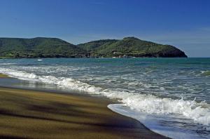 a view of the beach with a mountain in the background at Torre di Baratti Bio Resort in Populonia