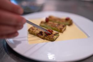 a person cutting a piece of food on a plate at Torre di Baratti Bio Resort in Populonia