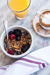 a bowl of breakfast cereal with berries and a cup of coffee at Kimpton Hotel Wilshire, an IHG Hotel in Los Angeles