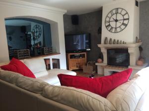 a living room with a couch and a clock on the wall at LA BASTIDE DES 3 AS & Spa in Vriange