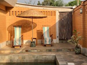 a patio with two chairs and an umbrella at Hôtel Amédzépé in Palimé