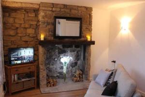 a living room with a stone fireplace with a tv at Haworth Bronte House Cottage in Haworth