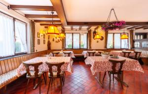 ein Restaurant mit Tischen, Stühlen und Fenstern in der Unterkunft Pension Schlossbergblick in Simonswald