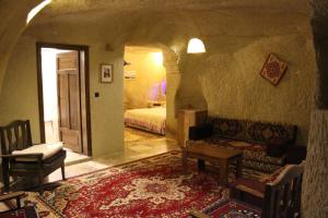 a living room with a couch and a bed in a room at Dilek Tepesi Cave Hotel in Ayvalı