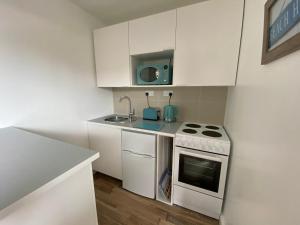 a white kitchen with a stove and a sink at Margate Seaside Retreat in Margate