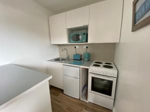 a white kitchen with a stove and a sink at Margate Seaside Retreat in Margate