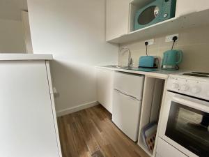 a small kitchen with white cabinets and a stove at Margate Seaside Retreat in Margate