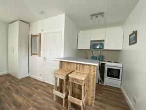 a kitchen with white cabinets and a counter with stools at Margate Seaside Retreat in Margate