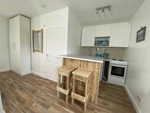 a kitchen with white cabinets and a counter with wooden stools at Margate Seaside Retreat in Margate