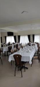 a large dining room with white tables and chairs at Hotel Rabbit Bran in Moieciu de Jos