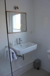a white bathroom with a sink and a mirror at Lohmann`s in Garstedt