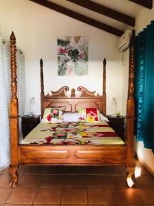 a bed with a wooden frame in a room at Mango Sea -Villa "Maracudja" et appartement "Jojoba" avec piscine & vue sur les îles in Saint-François