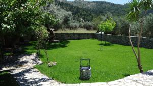 a yard with a large lawn with a stone wall at House of Garden in Dhráganon