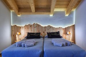 two beds in a room with a wooden wall at PiodaHaus B&B in Piedilago