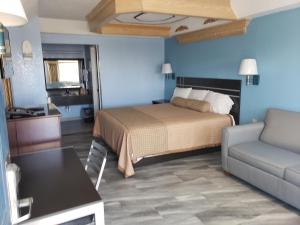 um quarto com uma cama, um sofá e uma mesa em Regency Inn Motel by the Beach em Corpus Christi