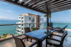 uma mesa e cadeiras numa varanda com vista para o oceano em Shangri La Luxury Penthouse Condominiums by Cheap Getaway em Puerto Vallarta