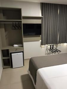 a bedroom with a bed and a desk with a television at Hotel Barreto in Nossa Senhora da Glória