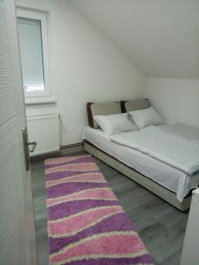 a small bedroom with a bed and a pink rug at Apartman All seasons in Sarajevo