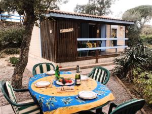 a table with chairs and a bottle of wine and a house at Chalet à Gassin au calme sous les pins in Gassin