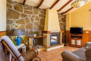 sala de estar con chimenea de piedra y TV en Villa Olympo, en Torrox