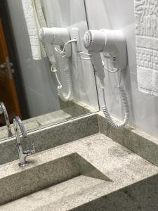 a bathroom sink with a hair dryer in front of a mirror at Hotel Barreto in Nossa Senhora da Glória