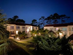 a hotel at night with palm trees and buildings at Punta del Este Arenas Hotel in Punta del Este