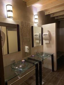 baño con 2 lavabos de cristal y espejos en Punta del Este Arenas Hotel, en Punta del Este