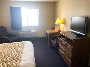 a hotel room with a bed and a television at Travelodge by Wyndham Grand Island in Grand Island