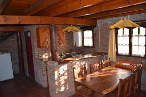 a dining room with a wooden table and a kitchen at Cabañas La Rosada in Santa Rosa de Calamuchita