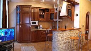 a kitchen with a bar with stools and a tv at Park Apartment in Lviv