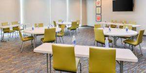 a room with tables and chairs and a flat screen tv at Holiday Inn Express - Alliance, an IHG Hotel in Alliance