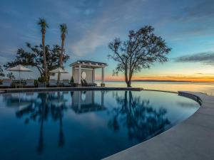 a swimming pool with a view of the water and palm trees at The Lodge at Sea Island in Saint Simons Island