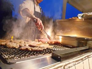 a man is cooking meat on a grill at Zielona Weranda in Wieluń