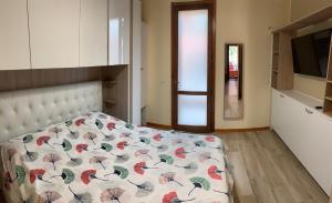 1 dormitorio con 1 cama con edredón de flores y TV en Casa Bea, en Cremona