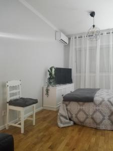 a white bedroom with a bed and a chair at Secondlove in Porto